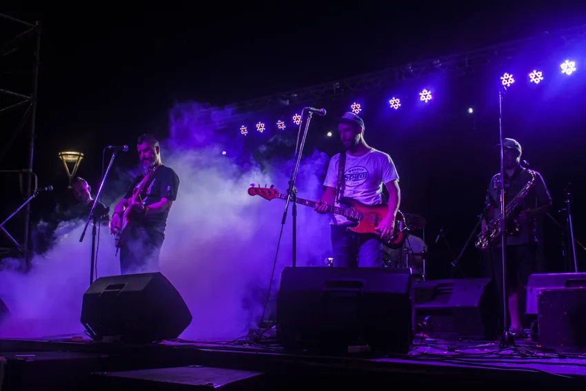 Músicos en el escenario iluminados por luces violetas