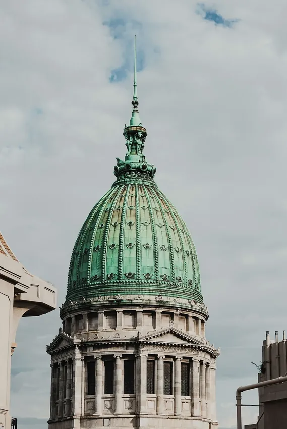 Cúpula arquitectónica verdosa frente a un cielo nublado